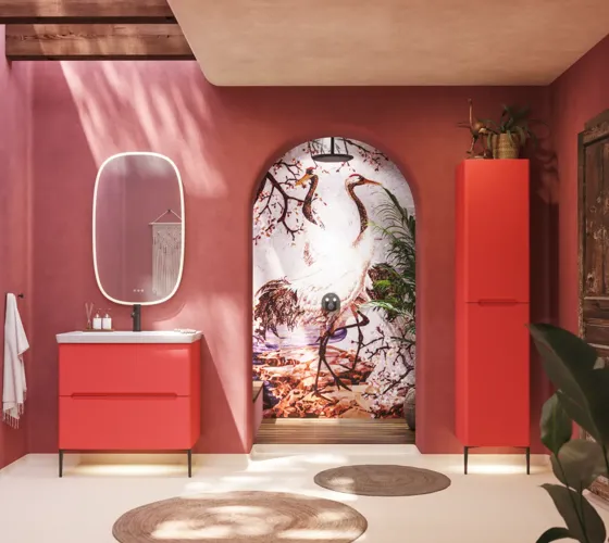 Badezimmer-Inspiration mit roten Wänden, sanft geformtem roten Waschtischunterschrank und Hochschrank, elegantem weißen Waschbecken und schönem ovalem Spiegel mit Beleuchtung, die zusammen mit der natürlichen Umgebung ein Vintage-Flair schaffen