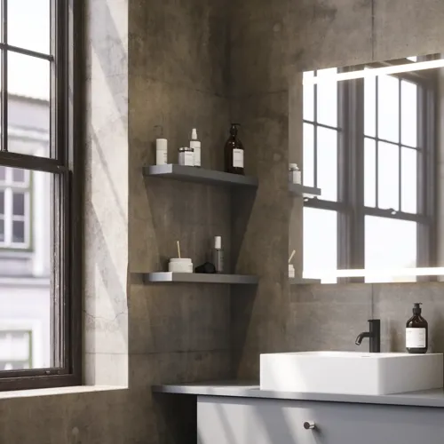 Badezimmer mit schrägen Wänden, grauem Waschtisch und Oberschrank, maßgefertigte Arbeitsplatten, modernes quadratisches Aufsatzwaschbecken, quadratischer Spiegel mit Beleuchtung, rohe Betonwände und -böden verleihen einen urbanen Ausdruck