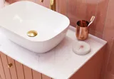 Großes Vintage-Badezimmer mit terrakottafarbenem Waschtisch, Aufsatzwaschbecken, ovalem Spiegel mit Messingrand, rosa und grauen Fliesen, romantisch und feminin