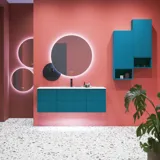 Große Badezimmerinspiration mit blauen Möbeln in Sonderfarbe mit Rillen, dünnem elegantem Waschbecken und schönen runden Spiegeln, roten Wänden und Terrazzoboden schaffen einen starken Kontrast zu den Möbeln und verleihen ein stilvolles, urbanes Aussehen.
