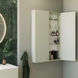 Stilvolles und luxuriöses Badezimmer mit sanften grünen Nuancen, einem großen eleganten runden Spiegel und einer modernen, raffinierten grünen Toilette