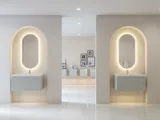 Stilvolle und moderne Badezimmer Inspiration mit ovalen Spiegeln mit Lichtsteuerung, Steinwaschbecken und Waschtischunterschränken mit eleganten Rillen in einem minimalistischen Design, helle und luftige Atmosphäre, elegante Beleuchtung