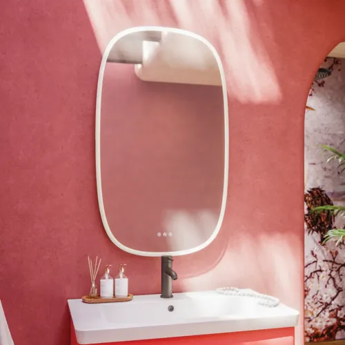Badezimmer-Inspiration mit roten Wänden, sanft geformtem roten Waschtischunterschrank und Hochschrank, elegantem weißen Waschbecken und schönem ovalem Spiegel mit Beleuchtung, die zusammen mit der natürlichen Umgebung ein Vintage-Flair schaffen