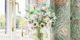 Badezimmerinspiration mit grünen Möbeln in Sonderfarbe mit Seiten aus naturbelassener Eiche, eleganten Rillen, stilvoller Arbeitsplatte mit ovalem Aufsatzwaschbecken, schönem ovalem Spiegel und Blumenmuster-Tapete für ein anmutiges, Retro-Aussehen.