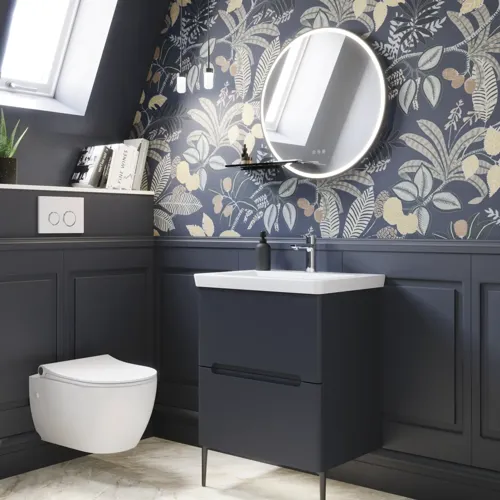 Badezimmer-Inspiration mit dunkelblauen Wandpaneelen, romantischer Blumen-Tapete, dunkelblauem Waschtischunterschrank mit weichen Formen und einem schönen runden Spiegel mit Beleuchtung, das ein Vintage-Flair verleiht