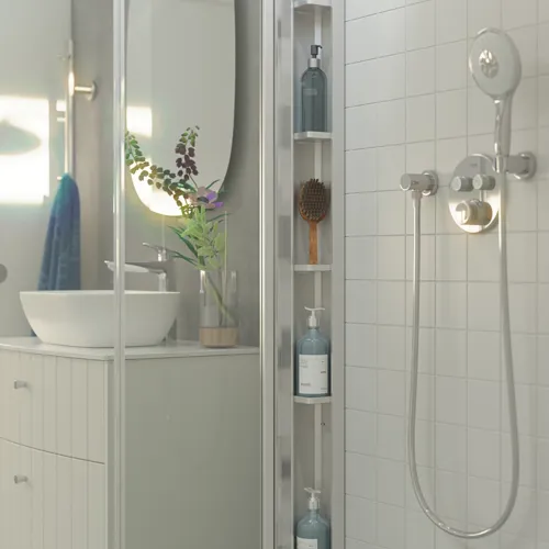 Badezimmerinspiration mit weißen Badezimmermöbeln, stilvoller Arbeitsplatte und Tischwaschbecken mit schönem ovalen Spiegel, Falttüren aus Klarglas und Satin sowie einer praktischen und eleganten Duschablage, die einen femininen Look verleiht.