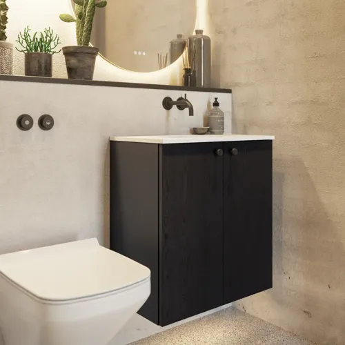 Badezimmerinspiration mit Waschtischunterschrank aus schwarzer Eiche sowie elegantem rundem Spiegel und Waschbecken, stilvollen Accessoires sowie Kaktuspflanzen und Wänden aus rohen Materialien verleihen einen rauen, industriellen und urbanen Look.