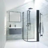 Badezimmer-Inspiration mit grauem Waschtischunterschrank mit quadratischem Spiegel mit schwarzem Rand und Lampe, abgerundeten Duschtüren in Klarglas und Profilen in Schwarz matt, mit elektrischem Handtuchtrockner und Badregal.