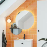 Badezimmer mit schräger Decke, inspiriert durch einen kleinen weißen Waschtisch und einen Hochschrank mit runden schwarzen Griffen, sowie einem schönen runden Spiegel, orangefarbene Fliesen geben einen frischen und modernen Look.