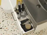 Kleine Badezimmerinspiration mit weißem Waschtisch mit schwarzem Griff und schwarzem elegantem Waschbecken, schönem rundem Spiegel mit schwarzem Rand, Terrazzo-Wand und -Boden und gelben Wänden für einen mutigen und modernen Look.