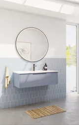Badezimmerinspiration mit hellblauen Fliesen und Betonboden, elegantem hellblauem Waschtischunterschrank mit schmalen Streifen, dünnem Waschbecken, doppeltem Hochschrank und rundem Spiegel mit schwarzem Rand und Licht.