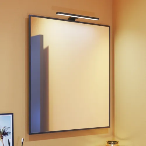 Kleine Badezimmerinspiration mit schrägen, warmen gelben Wänden und einem minimalistischen quadratischen Spiegel mit stilvollem schwarzen Rand, sowie einer eleganten Lampe für den Spiegel, die Ihrem Badezimmer einen Hauch von Eleganz verleiht.