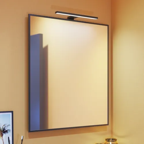 Kleine Badezimmerinspiration mit schrägen, warmen gelben Wänden und einem minimalistischen quadratischen Spiegel mit stilvollem schwarzen Rand, sowie einer eleganten Lampe für den Spiegel, die Ihrem Badezimmer einen Hauch von Eleganz verleiht.