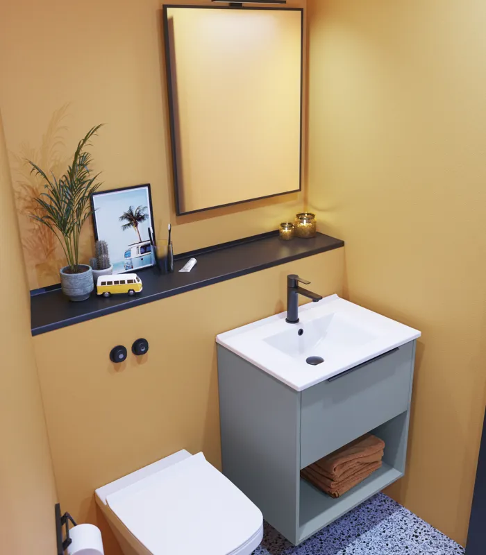 Kleine Badezimmerinspiration mit schrägen und warmen gelben Wänden, elegantem hellblauem Waschtisch, dünnem und stilvollem Waschbecken sowie minimalistischem quadratischem Spiegel mit schwarzem Rand und praktischer Lampe.