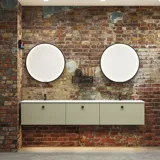 Rohes und modernes Badezimmer im urbanen Stil. Schöne Waschtischunterschränke und runde Spiegel mit schwarzer Zierleiste