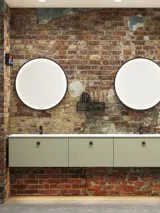 Rohes und modernes Badezimmer im urbanen Stil. Schöne Waschtischunterschränke und runde Spiegel mit schwarzer Zierleiste