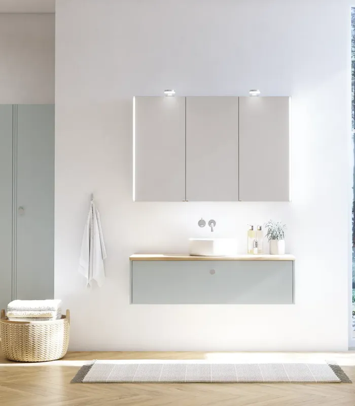 Große Badezimmerinspiration im nordischen Stil mit Badezimmerschränken in hellblauer Farbe und Holzarbeitsplatte mit elegantem Aufsatzwaschbecken, Fischgrät-Holzboden, der einen hellen und klassischen Stil schafft