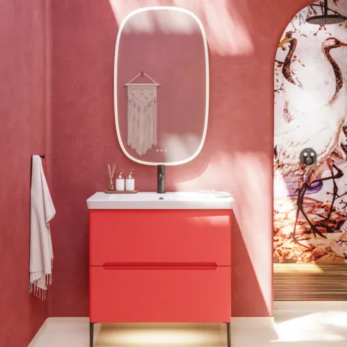Badezimmer-Inspiration mit roten Wänden, sanft geformtem roten Waschtischunterschrank und Hochschrank, elegantem weißen Waschbecken und schönem ovalem Spiegel mit Beleuchtung, die zusammen mit der natürlichen Umgebung ein Vintage-Flair schaffen