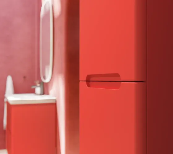 Badezimmer-Inspiration mit roten Wänden, sanft geformtem roten Waschtischunterschrank und Hochschrank, elegantem weißen Waschbecken und schönem ovalem Spiegel mit Beleuchtung, die zusammen mit der natürlichen Umgebung ein Vintage-Flair schaffen