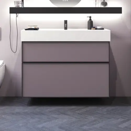 Badezimmer mit schrägen Wänden, inspiriert von lila Möbeln mit eleganten Rahmenfronten, ovalem Spiegel mit Lampe, praktischer Ablage, lila Wand und grauem Fischgrätenboden für einen eleganten, modernen Look.